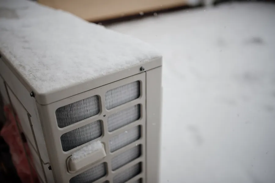 Unité extérieure de climatisation couverte de neige