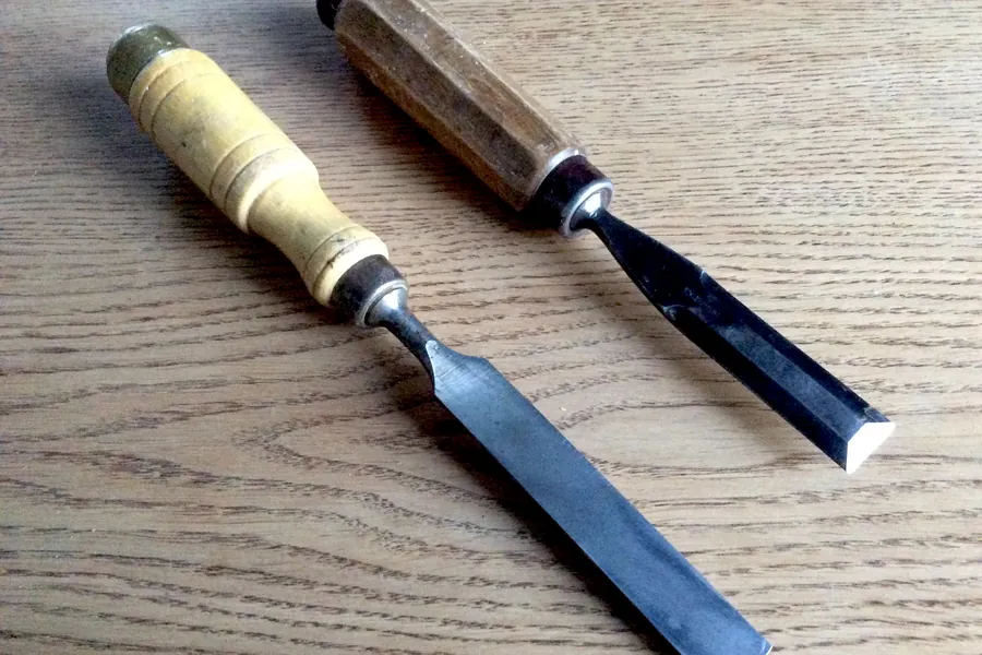 Deux ciseaux à bois à manche en bois posés sur un plateau en chêne