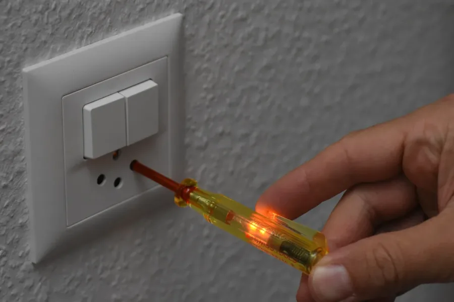 Testeur de tension électrique utilisé sur un interrupteur mural