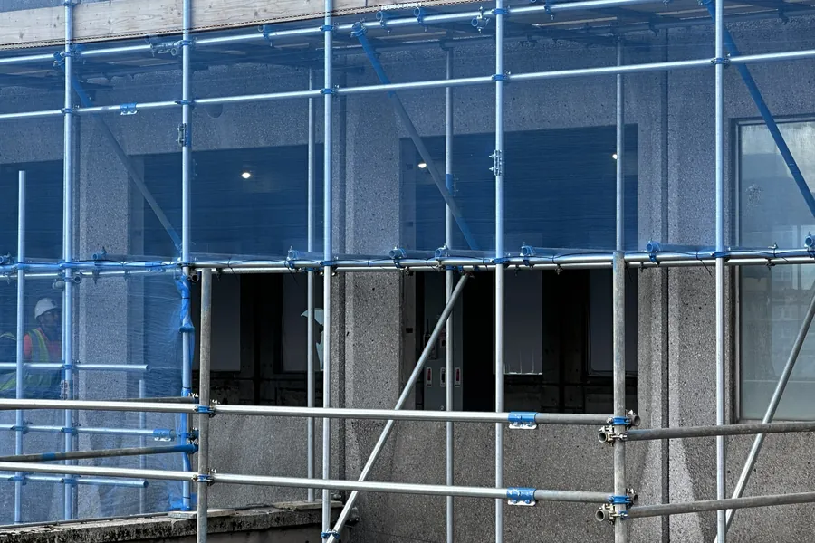 Échafaudage et filet de protection devant une façade en béton en cours de rénovation